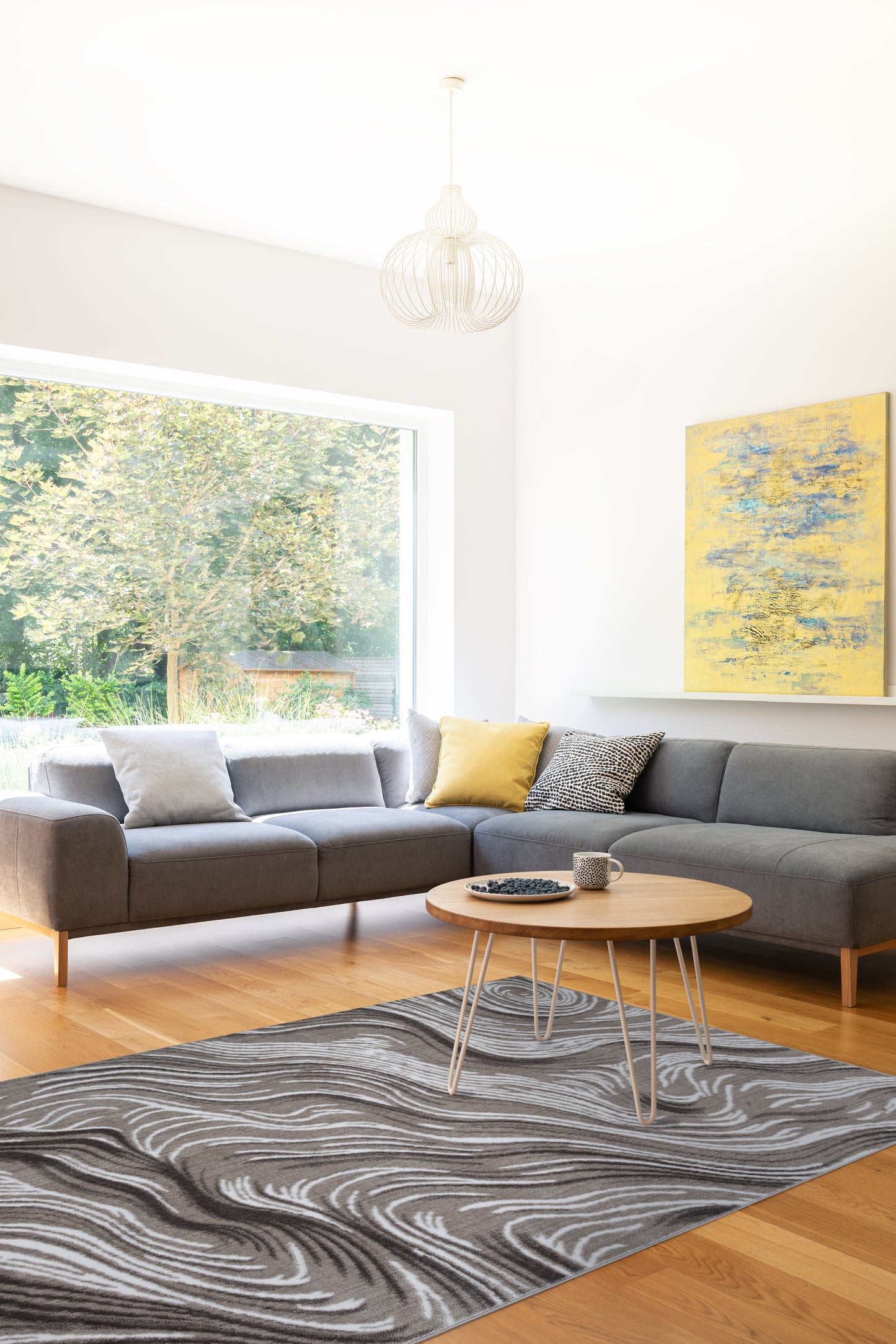 Modern living room with a gray sectional sofa, coffee table, and abstract painting.