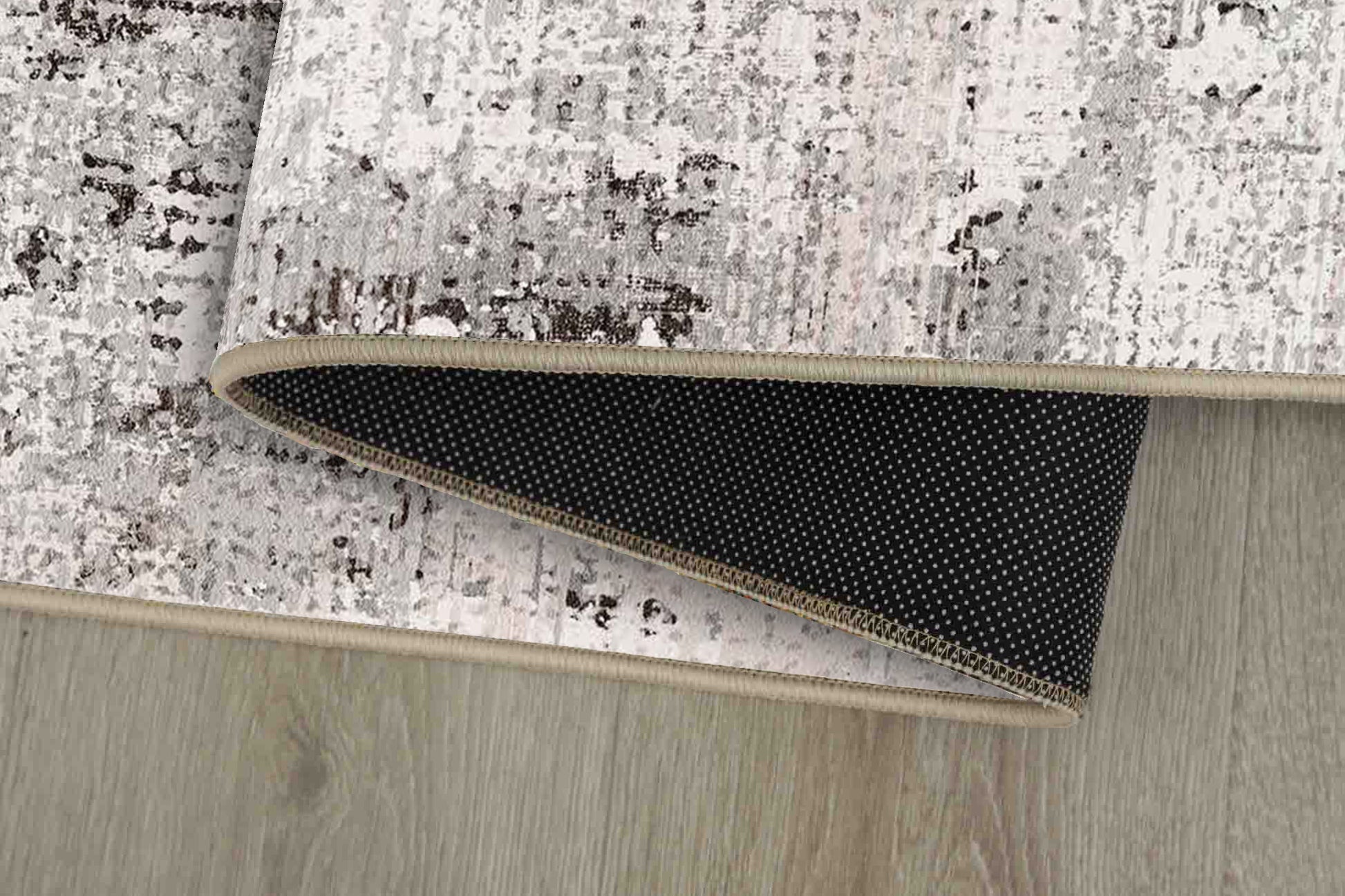 Torino Stone Border rug corner folded, showing the non-slip dot backing